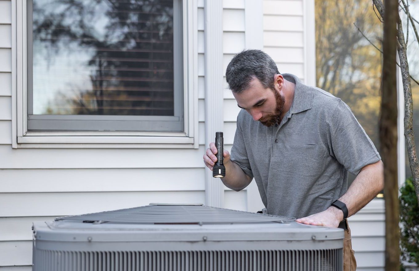 A technician inspecting an HVAC unit outdoors